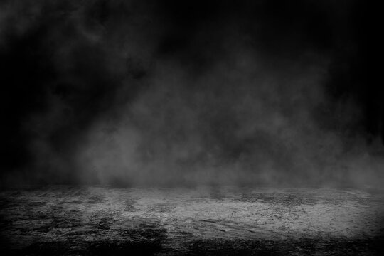 Concrete floor with smoke or fog in dark room with spotlight. asphalt street, black background