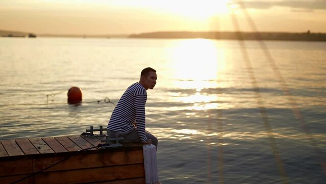 sunrise over sea in early morning, young man is admiring landscape sitting on wooden pier