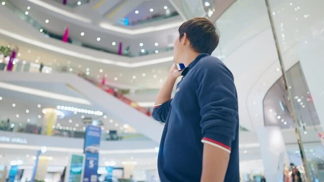 Young asian man calling his friends after get lost in the big department store, being lost in the city, mobile phone service carrier, modern lifestyle smart technology, make call seeking for friends