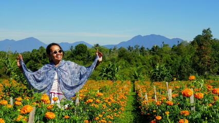charmant lächelnde Asiatin posiert in gelbem Blumenfeld in Bali unter blauem Himmel