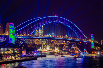 Fototapeta na wymiar 冬のシドニーのイベント・ビビッドシドニーで見た、青くライトアップされるハーバーブリッジと周辺の夜景