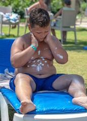 The boy puts on sunblock on a sunbed. Relaxation
