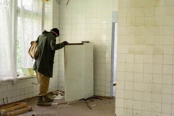 Wandering survivor. Man goes to an refrigerator in an abandoned building. Post apocalypse. Man traveling on foot in a post-apocalyptic world in search of food.