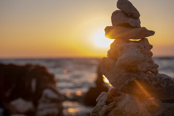 Stones stacked in a turret in the rays of the setting sun. Marine weathered limestone