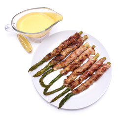 Healthy food - Asparagus wrapped with bacon and spices on a plate isolated on white background
