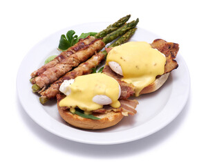 Healthy food - Asparagus wrapped with bacon and benedict poached eggs on a plate isolated on white background