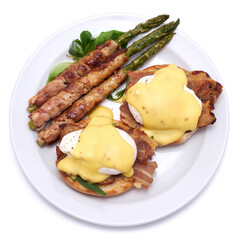 Healthy food - Asparagus wrapped with bacon and benedict poached eggs on a plate isolated on white background