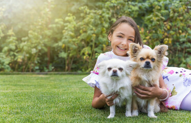 Pretty little girl is smiling at the camera posing with two cute dogs.  Horizontally. 