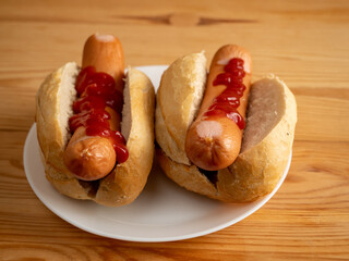 Boiled sausage with a bun on a wooden background.