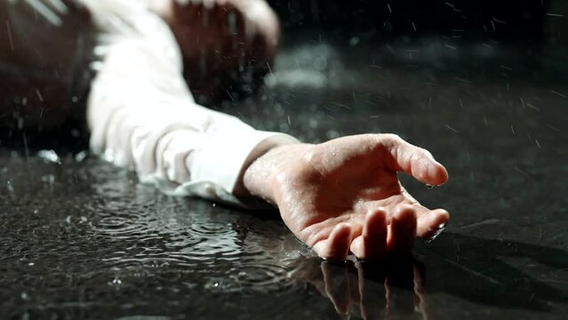 murder on street in night, dead man is lying in puddle on asphalt in city lane, corp of caucasian man