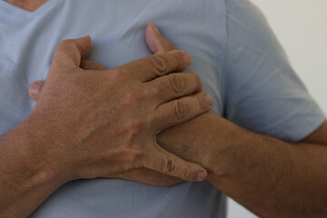 A man feeling chest pain. He is having a serious pain on chest. Close up shot of hands holding left part of chest. Healthcare concept, A man has severe heart pain and chest pain suffocating.