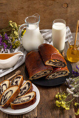 Roll with poppy seeds and a glass of milk. Food on the table. Sweet sweet pastries. Homemade simple yeast bun with filling. Breakfast on a wooden table. lactose and gluten. Honey spas