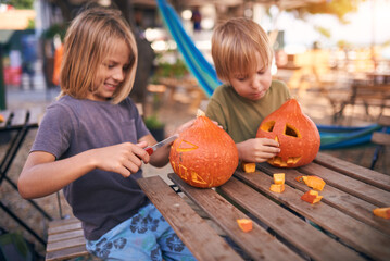 Young kids carving Halloween pumpkin