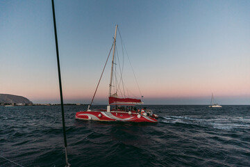 Red and white catamaran in Greece sailing at sunset