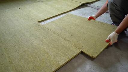 The builder insulates the floors of the house with glass wool. Laying glass wool on a concrete...