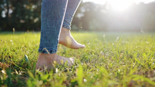 bare feet walking on the grass. a teenager girl takes off her shoes walking bare bare feet on the grass in the park in summer. happy family kid concept. bare feet close-up stepping dream on the grass