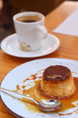  spanish flun pudding dessert closeup photo with teaspoon and cup of coffee on the background