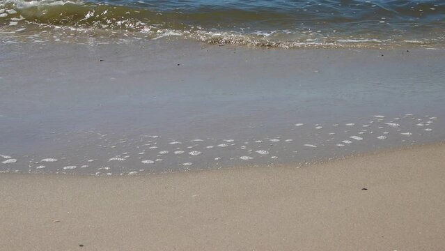 Breaking waves at a sandy beach on a sunny day