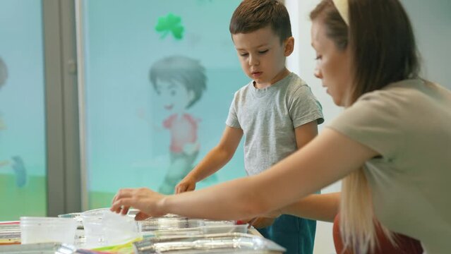 preschooler kid painting with paints on the water with his teacher, Ebru art, creative art for kids. High quality 4k footage