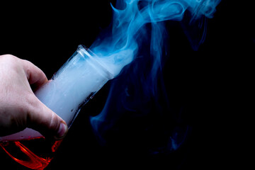 smoking chemicals, a glass flask with a chemical liquid held in the hand on a black background