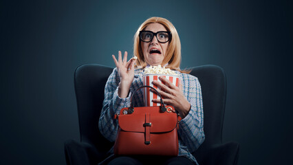 Funny woman watching a scary movie and eating popcorn
