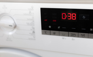 Modern white washing machine front panel with black display.
