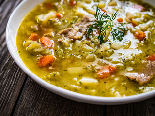 Bowl of hot cabbage soup on wooden table
