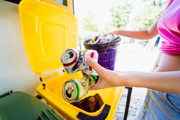 A young beautiful girl throws sorted garbage into special bins