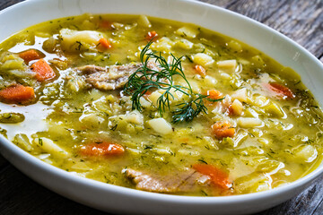 Bowl of hot cabbage soup on wooden table

