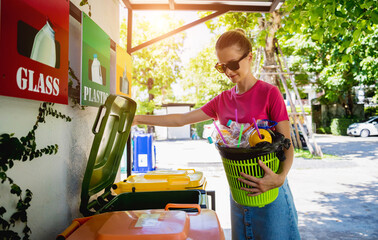 A young beautiful girl throws sorted garbage into special bins