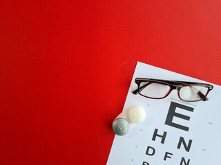 Vision check glasses and lenses for vision correction on red background top view