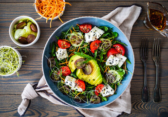 Fresh salad - manouri cheese, avocado, grapes and green vegetables on wooden table 