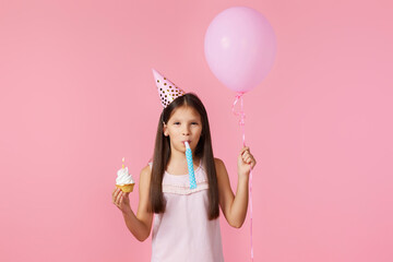 happy little birthday girl with party cone holding cupcake