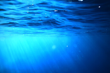 Obraz premium ocean underwater rays of light background, under blue water sunlight