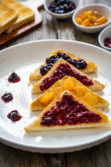 Toasted bread with fruit jam on wooden background
