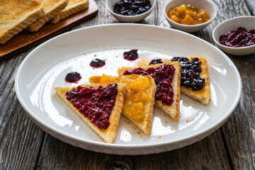 Toasted bread with fruit jam on wooden background
