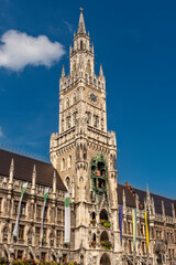 Die im Stil der Neugotik gestaltete Fassade des neuen Rathaus mit Rathausturm in der Altstadt von München in Unteransicht vom Marienplatz aus gesehen bei schönem Sommerwetter und blauen Himmel