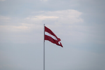 Waving national flag of Latvia in red white red color on sky background