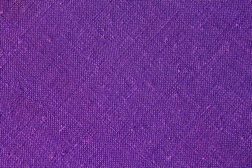 Abstract design background of violet coarse-grained intersection texture of rough fabric with an interlacing. Linen sack textile canvas burlap cloth. Witch hat halloween color. Close up, top view