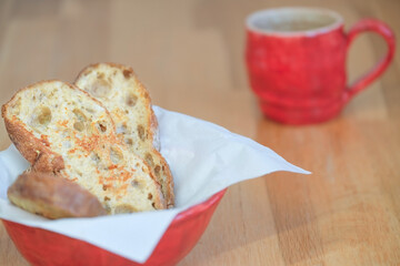 Plate with egg fried bread with big whole next to red cup on wooden table
