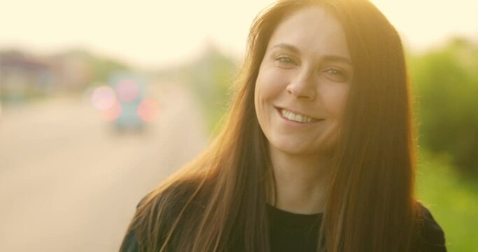 Portrait of beautiful girl smiling and looking at camera during sunset. Open portrait smiling girl. Slow motion