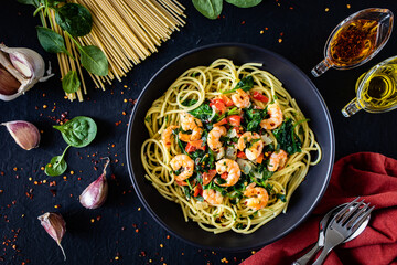 Spaghetti with prawns and spinach on wooden table
