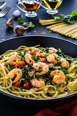 Spaghetti with prawns and spinach on wooden table
