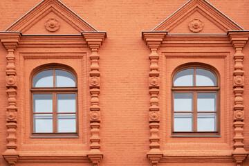 Red brick wall with two carved windows