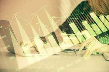 Double exposure of woman on-line shopping holding a credit card and financial graph drawing. Stock market E-commerce concept.