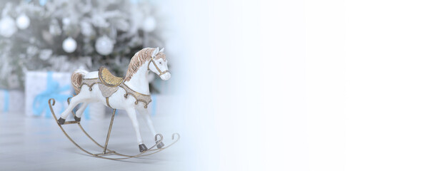 Toy horse on the background of a Christmas tree with gifts.Copy space for text. Banner