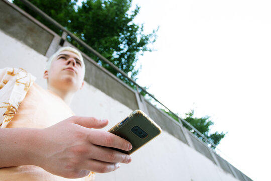 boy seen from below holding a cell phone in the foreground