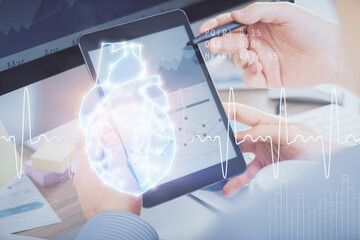 Double exposure of man's hands holding and using a phone and heart drawing. Medical education concept.