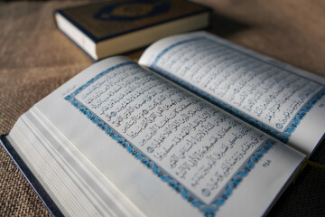Fototapeta premium Kudus, Indonesia - August, 2022 : The Quran, also romanized Qur'an or Koran, is the central religious text of Islam, believed by Muslims to be a revelation from God (Allah). Brown sack background.