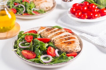 Fototapeta na wymiar Salad with grilled chicken fillet meat, fresh vegetables, spinach, ruccola, red onion and tomato. Healthy menu. Diet food. Top view. Banner 